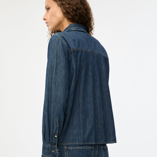 Person wearing a blue denim jacket on a white background