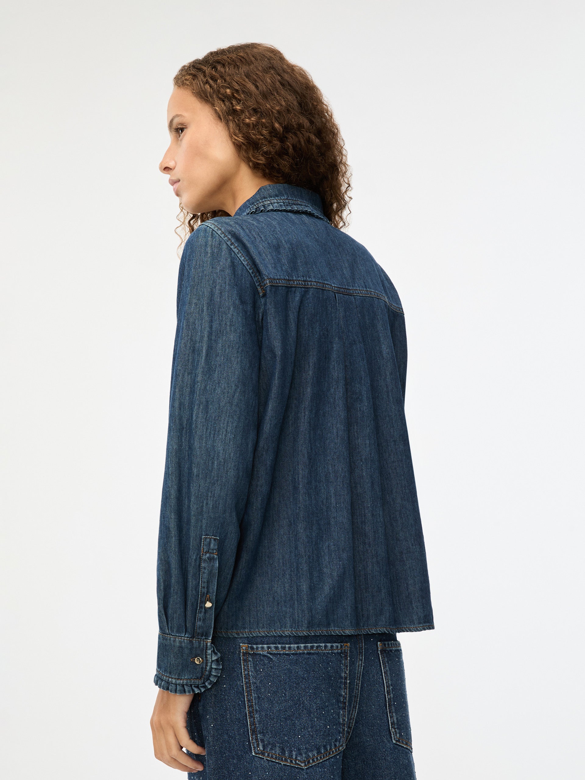 Person wearing a blue denim jacket on a white background