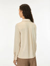 A woman shown from the back wearing a light beige long-sleeve blouse and brown checkered trousers against a plain white studio background.