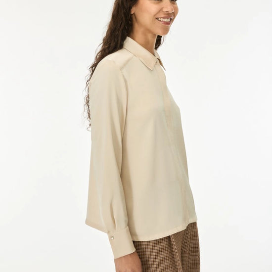 woman wearing cream satin shirt on a white background side view