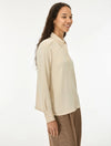 woman wearing cream satin shirt on a white background side view