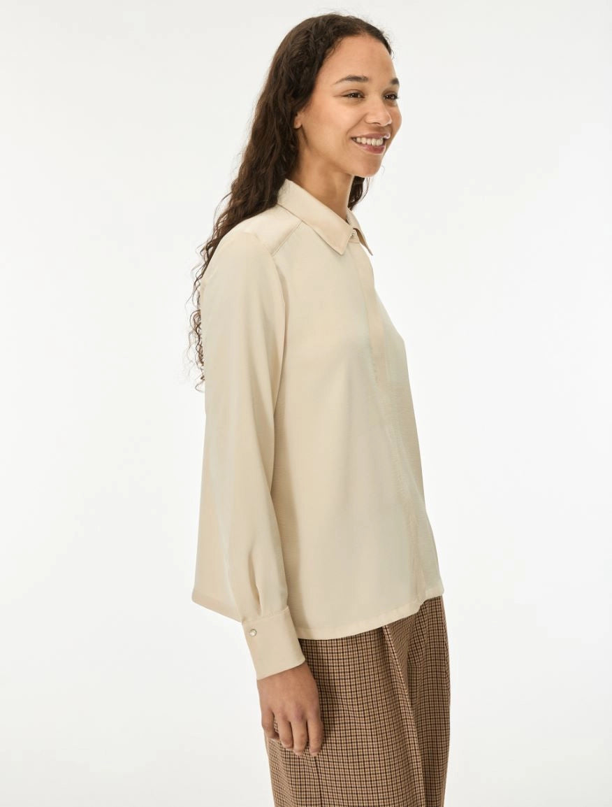 woman wearing cream satin shirt on a white background side view