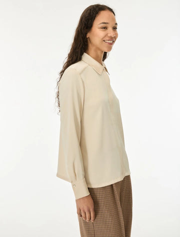 woman wearing cream satin shirt on a white background side view