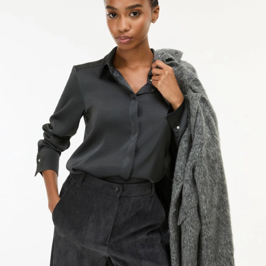 woman wearing grey satin shirt on a white background side view