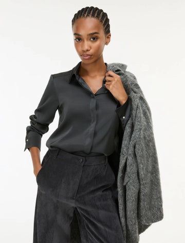 woman wearing grey satin shirt on a white background side view