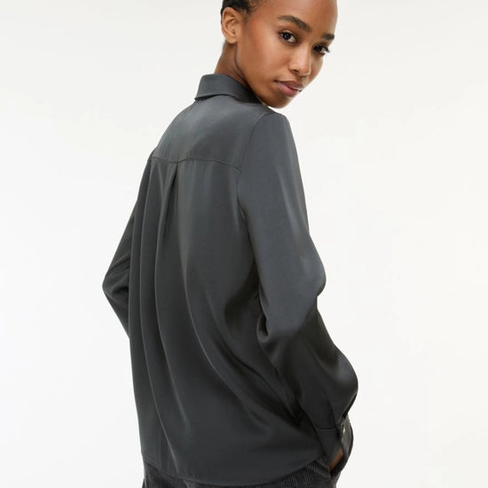 woman wearing grey satin shirt on a white background side view