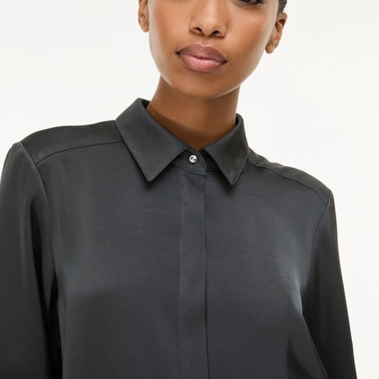 woman wearing grey satin shirt on a white background side view