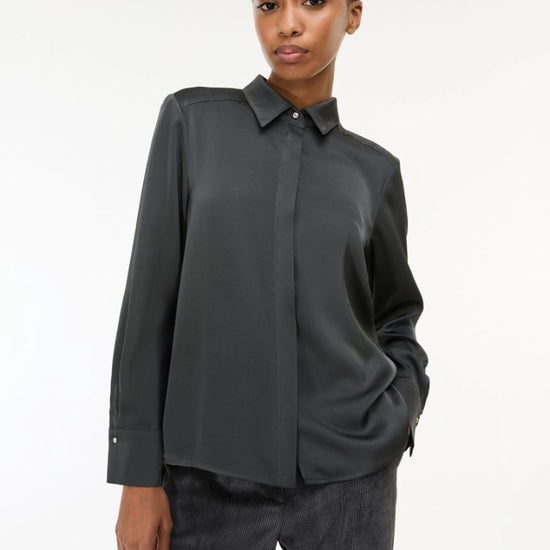 woman wearing grey satin shirt on a white background side view