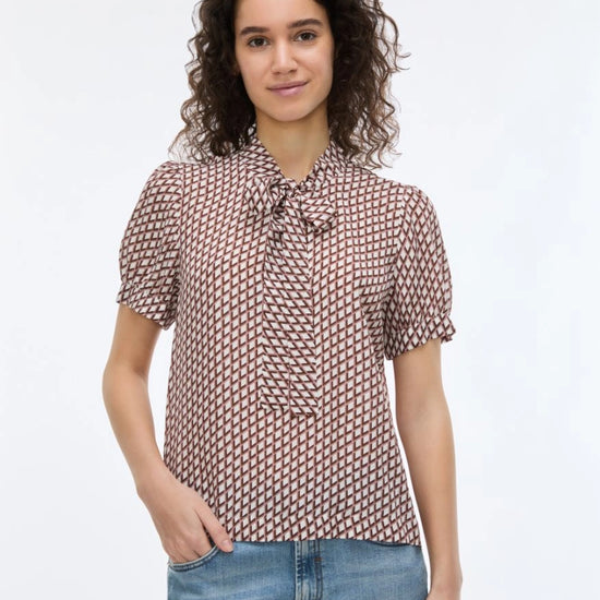woman wearing geometric blouse with neck tie on white background