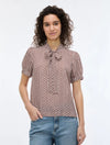 woman wearing geometric blouse with neck tie on white background