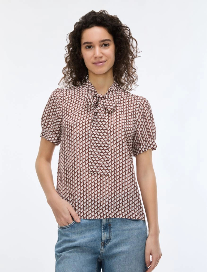 woman wearing geometric blouse with neck tie on white background
