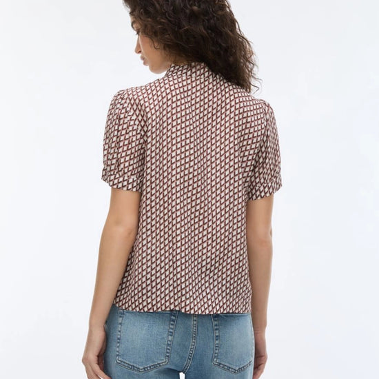 woman wearing geometric blouse with neck tie on white background rear view