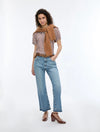 woman wearing geometric blouse with neck tie and jeans on white background
