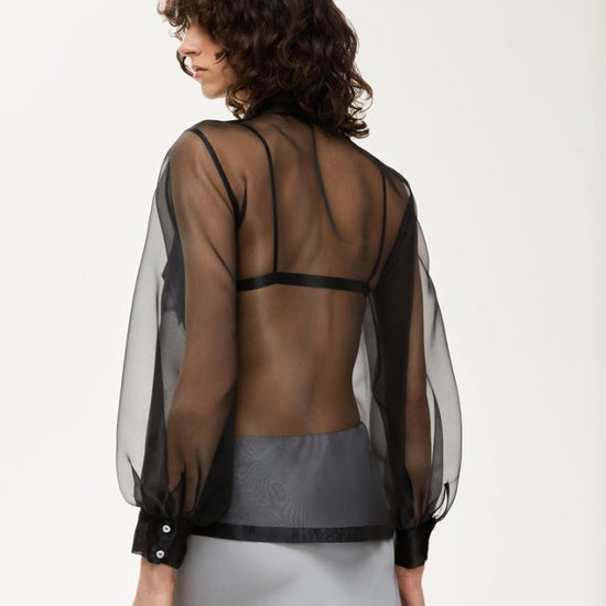 black sheer blouse with tie neck, long puffy sleeves and chest pockets rear view 
