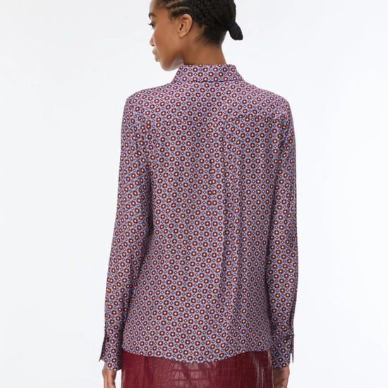 woman wearing a blue and red pattern shirt and red skirt on a white background rear view