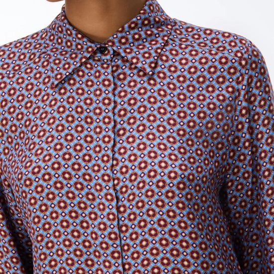 close up of a woman wearing a blue and red pattern shirt and red skirt on a white background