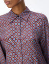 close up of a woman wearing a blue and red pattern shirt and red skirt on a white background
