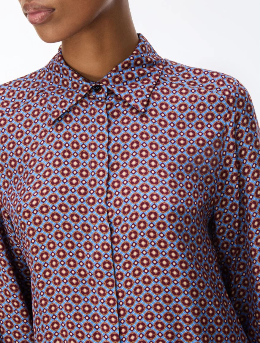 close up of a woman wearing a blue and red pattern shirt and red skirt on a white background