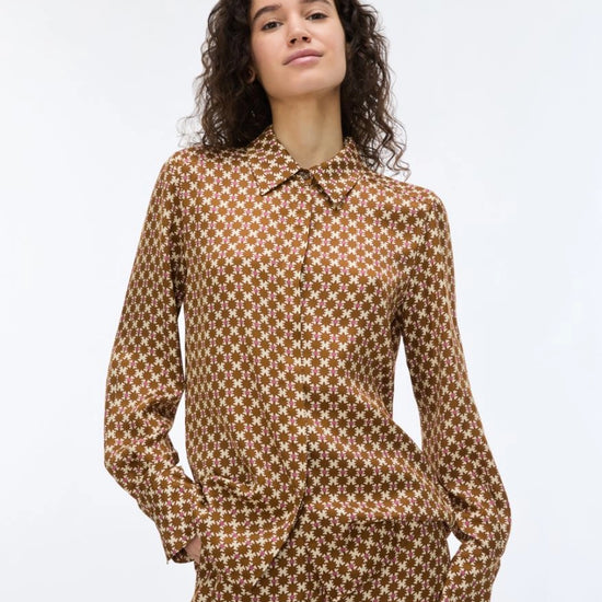 woman wearing a geometric brown and cream shirt on a white background
