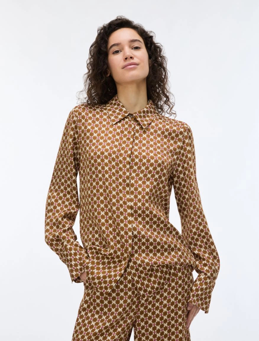 woman wearing a geometric brown and cream shirt on a white background