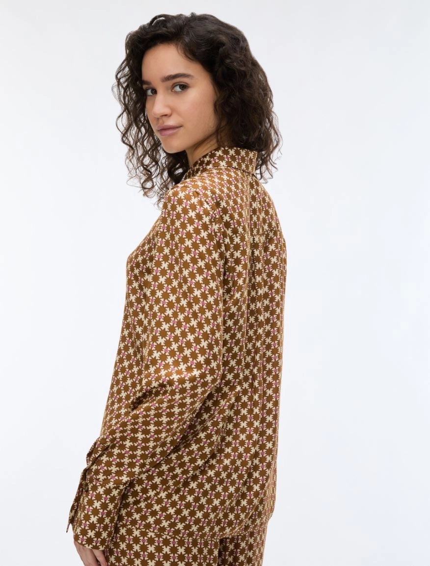 woman wearing a geometric brown and cream shirt on a white background rear view