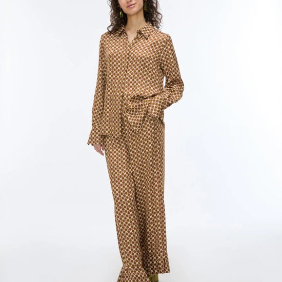 woman wearing a geometric brown and cream shirt with matching trousers on a white background
