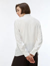 A woman with a short brown bob haircut is shown from the back wearing a white long-sleeve button-up shirt and dark brown pinstriped trousers, set against a plain white studio background.