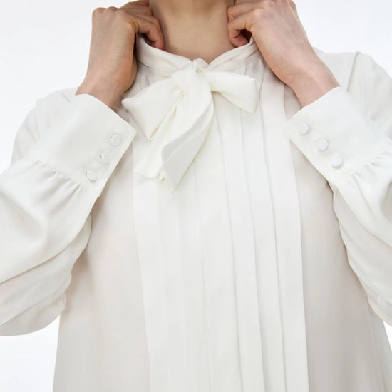white blouse with neck tie on white background close up 