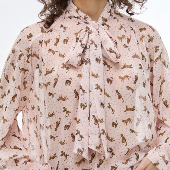 Woman wearing a patterned blouse with a tie neckline on a white background
