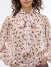 Woman wearing a patterned blouse with a tie neckline on a white background