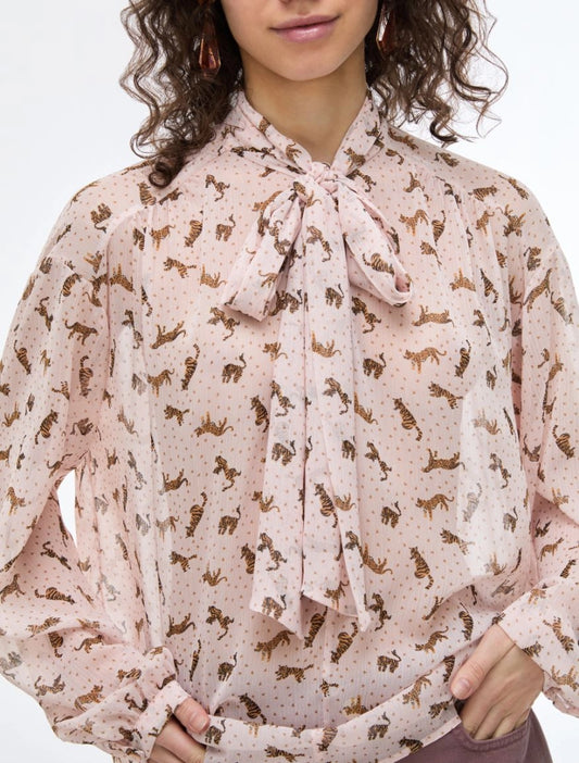 Woman wearing a patterned blouse with a tie neckline on a white background