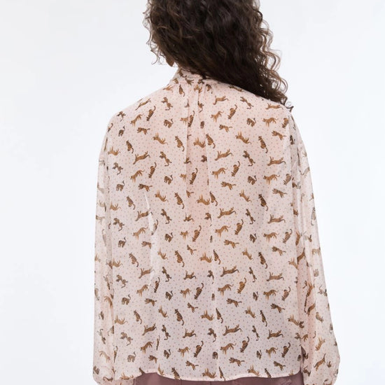 Person wearing a light-colored blouse with a subtle pattern on a white background
