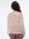 Person wearing a light-colored blouse with a subtle pattern on a white background