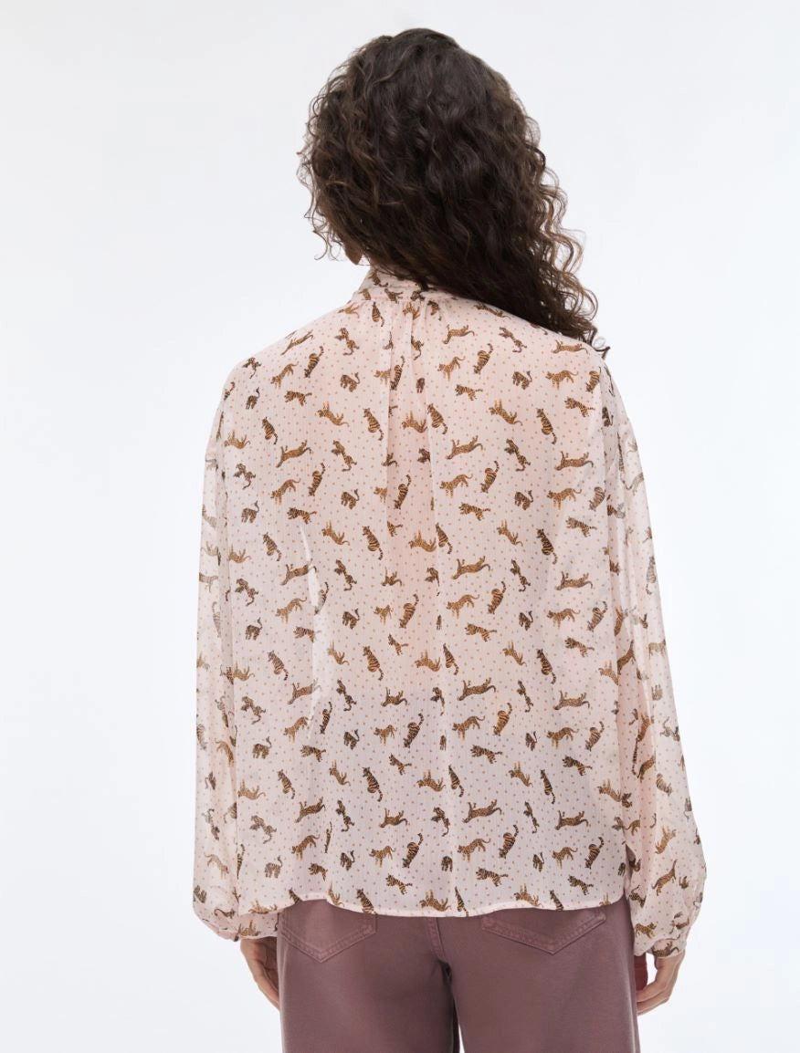 Person wearing a light-colored blouse with a subtle pattern on a white background