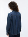A person shown from the back wearing a dark blue denim long-sleeve button-up shirt and dark jeans against a plain white studio background.