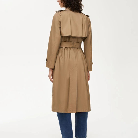 Woman wearing a beige trench coat on a white background