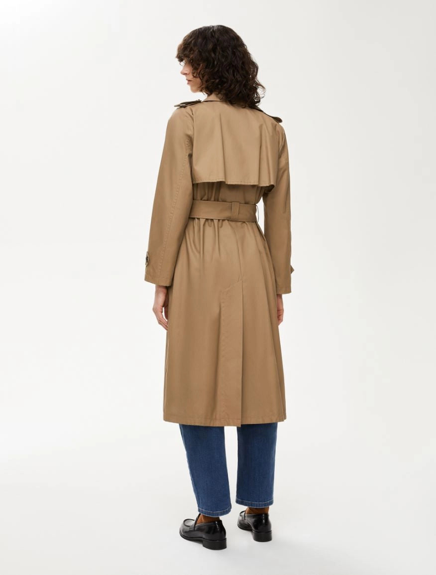 Woman wearing a beige trench coat on a white background