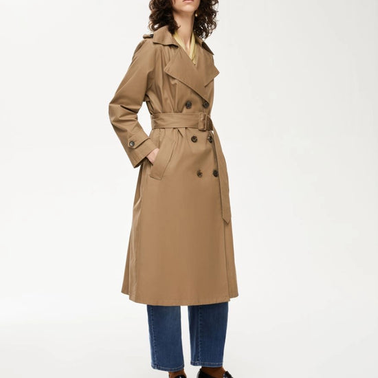Woman wearing a beige trench coat on a white background