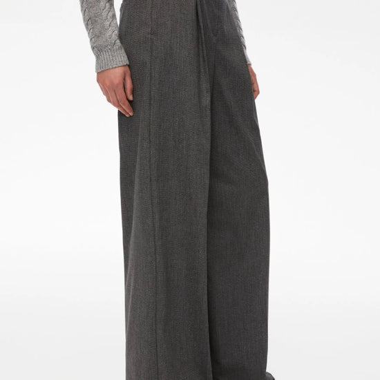 Person wearing gray wide-leg pants and a gray sweater on a white background side view