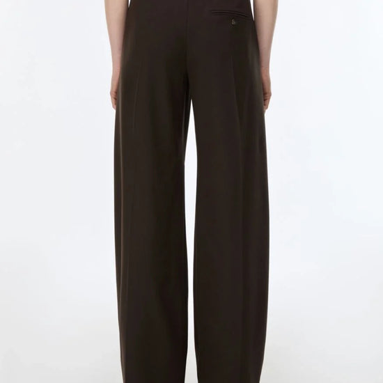 A model shown from the back wearing dark brown wide-leg trousers, photographed against a clean white studio background.