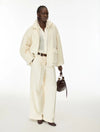 Woman wearing cream fur jacket and trousers on a white background