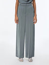 A model wearing slate blue wide-leg trousers with a matching waistband, paired with silver sandals, shown from the waist down on a white studio background.
