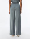 A model shown from the back wearing high-waisted, wide-leg trousers in a muted slate gray color, paired with a matching gray top and metallic heels, against a plain white studio background.