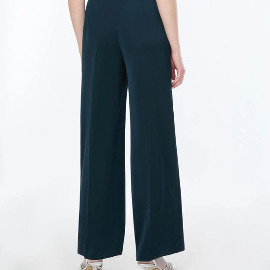 woman wearing Blue satin trousers on a white background rear view