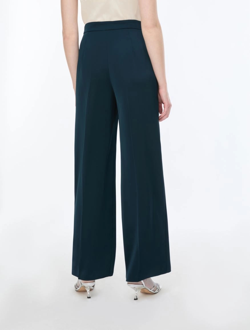 woman wearing Blue satin trousers on a white background rear view