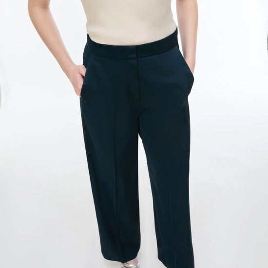 woman wearing Blue satin trousers  and white cami on a white background