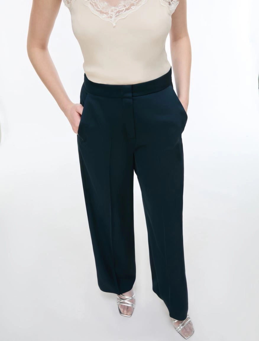 woman wearing Blue satin trousers  and white cami on a white background