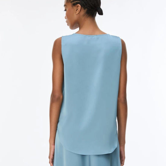 The back of model wearing a light blue sleeveless silk top.