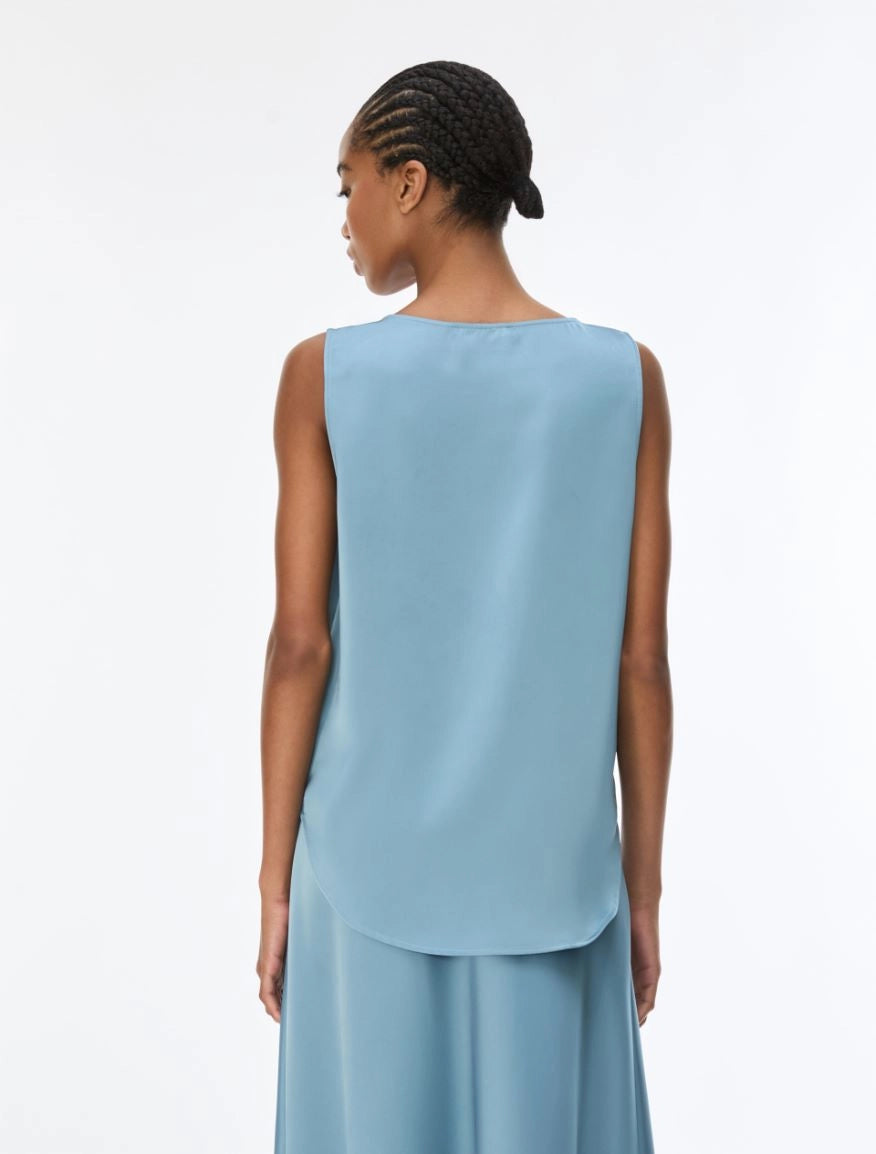 The back of model wearing a light blue sleeveless silk top.