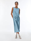 A woman modeling a sleeveless light blue top with a tied waist, paired with clear high-heeled sandals, against a plain white studio background.